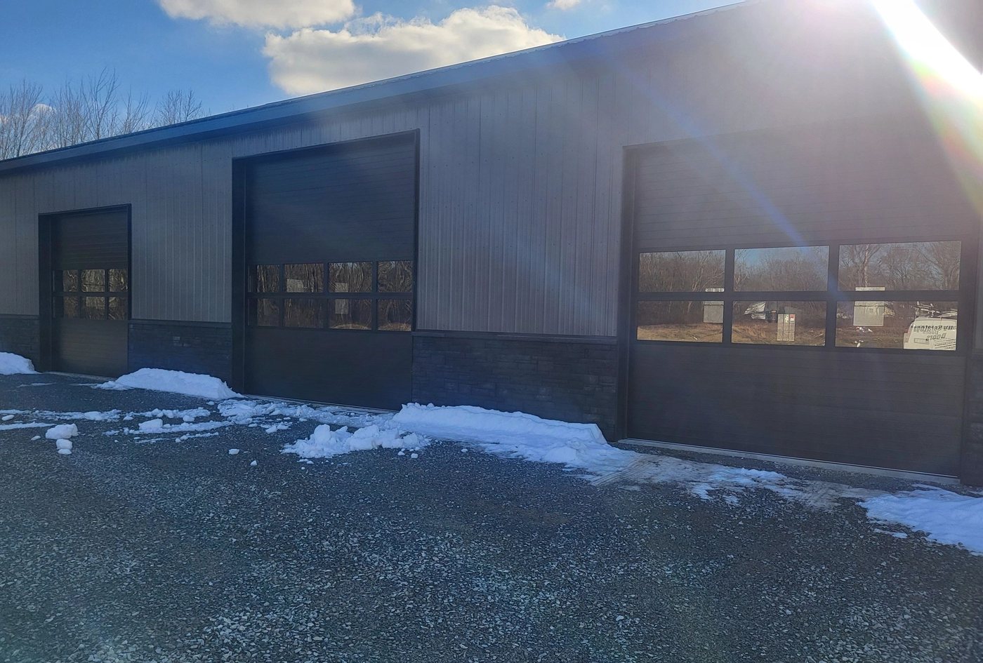 A long dark commercial front with matching dark doors, low winter sun and snow still on the ground.