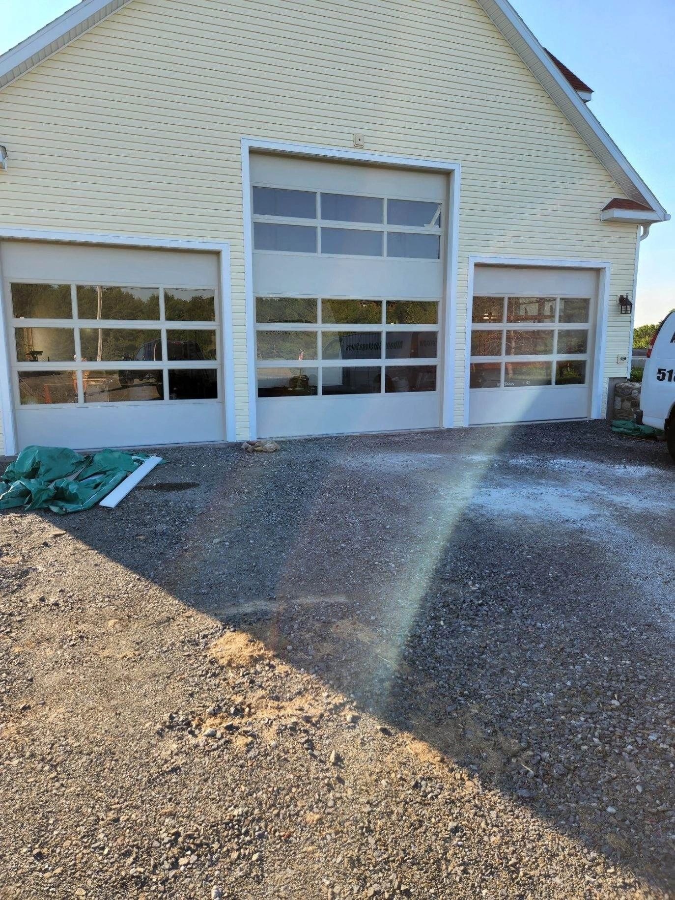 Three full-view glass doors in a cream gable end — a tall center bay between two shorter ones — on a freshly graded gravel drive.