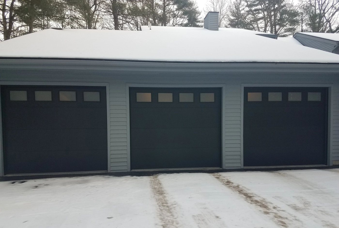 Three slate-gray doors along a low ranch garage.