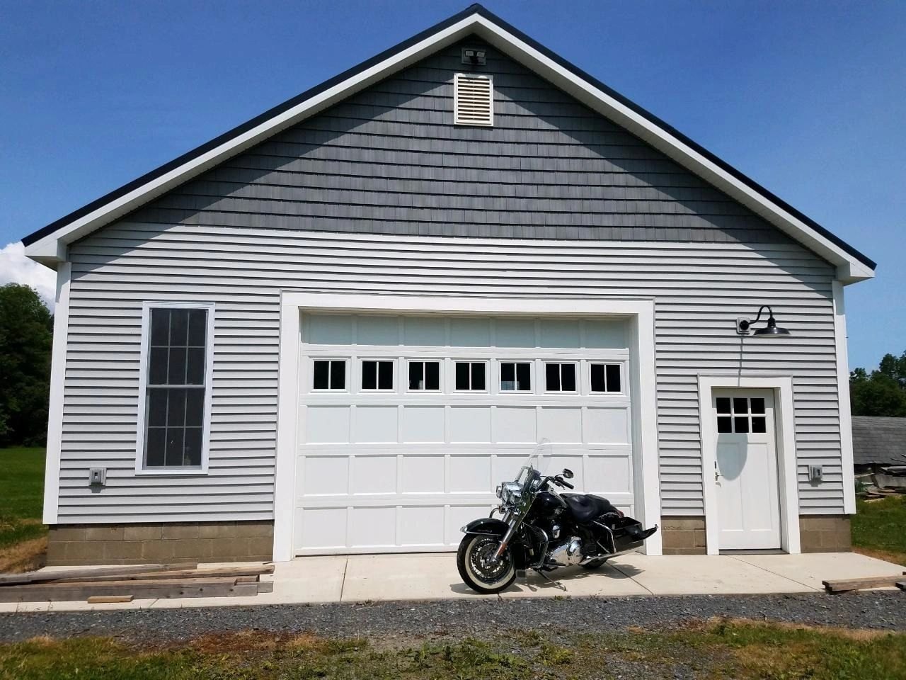 A white door with a full window row in a gray barn-style garage, a motorcycle parked alongside.